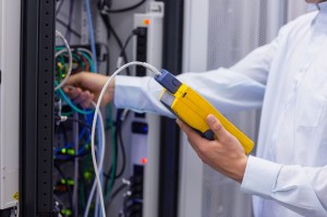 Technician using digital cable analyser on servers
